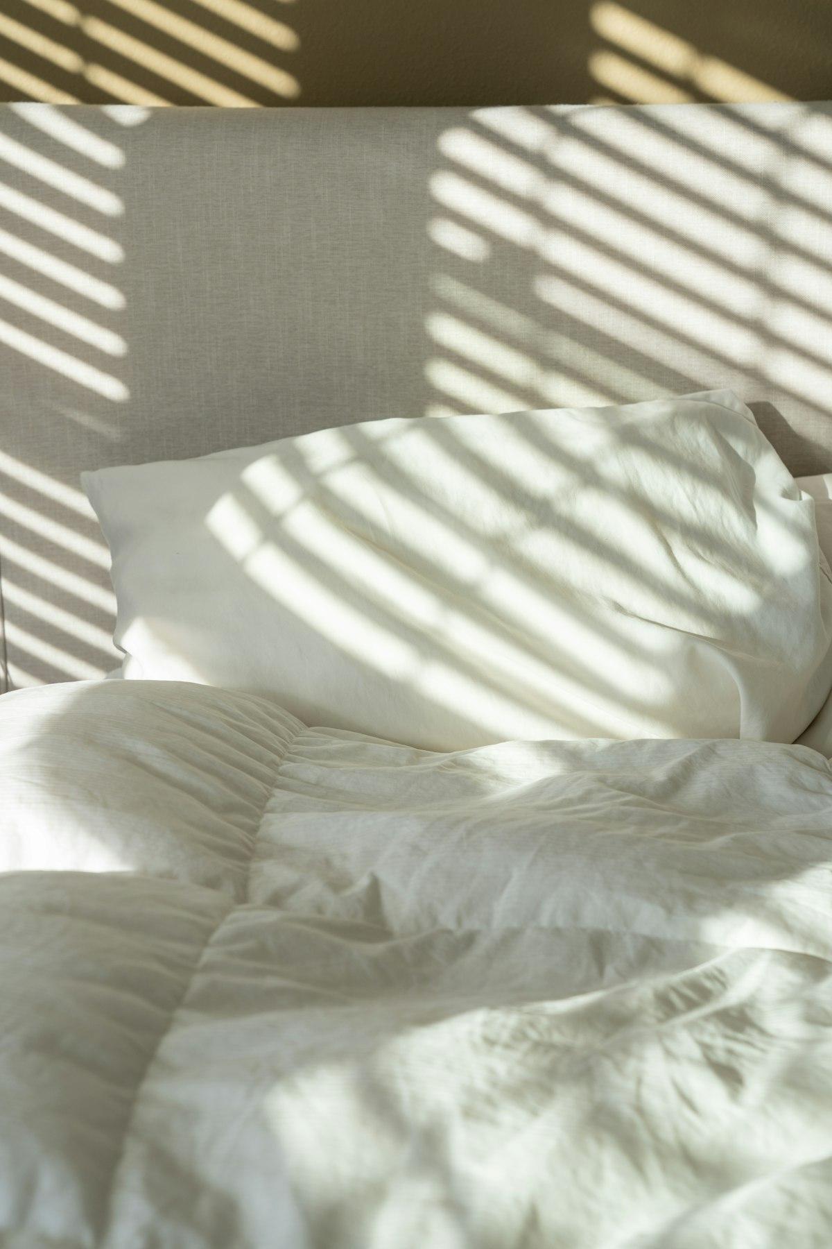 Bed with pillow in soft morning light through blinds